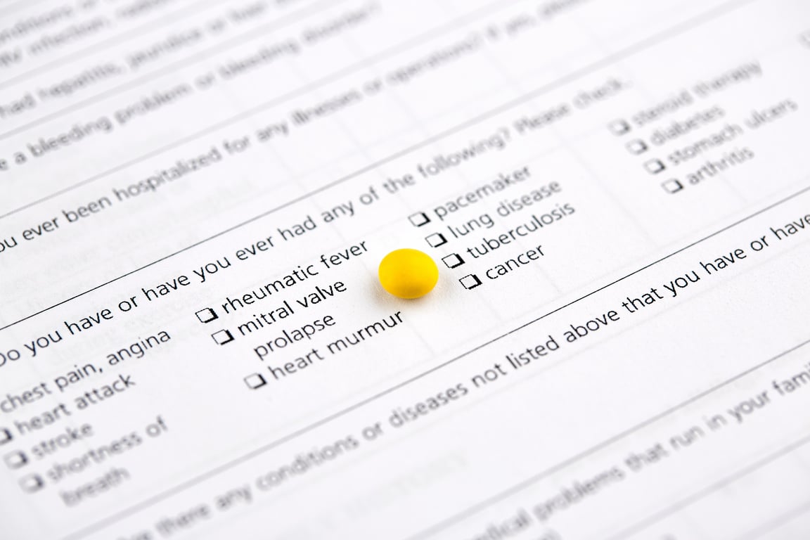 Small round yellow pill on medical questionnaire form